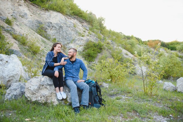 Chico excursionista le da una mano a la chica mientras camina en las montañas