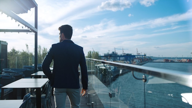 Chico exitoso yendo a la terraza en la vista trasera del café en la azotea Gerente de la empresa disfrutando