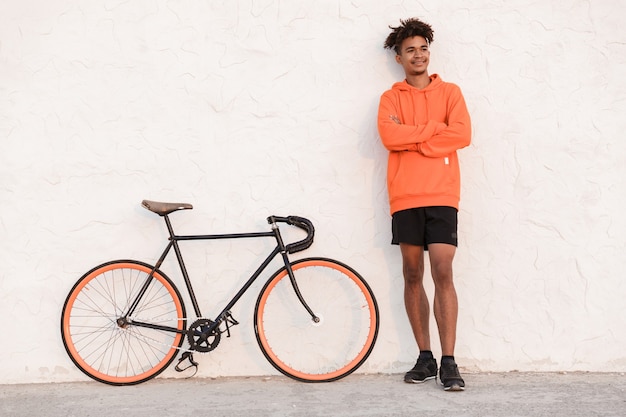 Chico feliz alegre deportes al aire libre en la playa con bicicleta