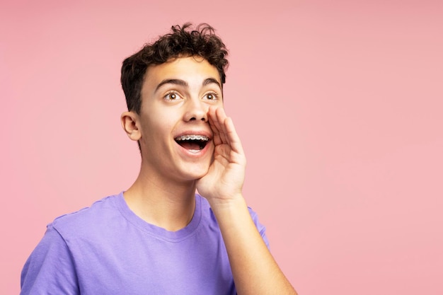 Un chico feliz y atractivo gritando algo anunciando mirando hacia otro lado en el espacio de copia un adolescente guapo