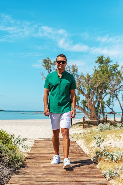 Chico feliz en la playa en pantalones cortos y camiseta