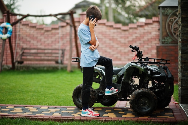 Chico en fourwheller ATV quad bike con teléfono móvil