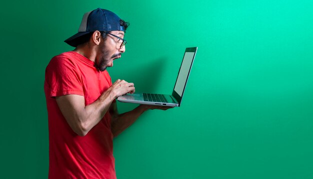 Chico con gorra revisando su computadora portátil aislado hombre sorprendido revisando su computadora portátil
