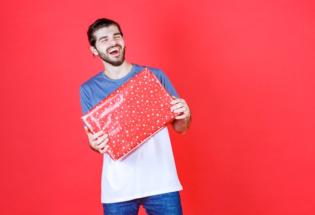 Chico guapo alegre con gran caja de regalo