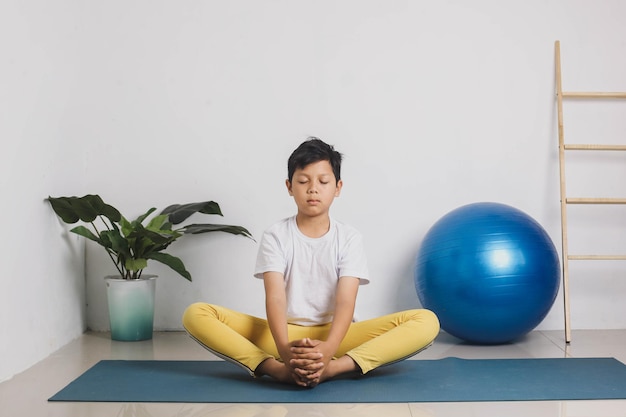 Chico guapo asiático está meditando en casa