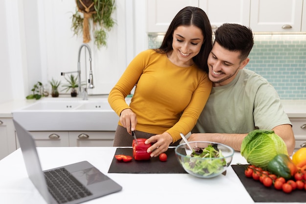 Chico guapo ayudando a su linda novia a hacer la cena en casa