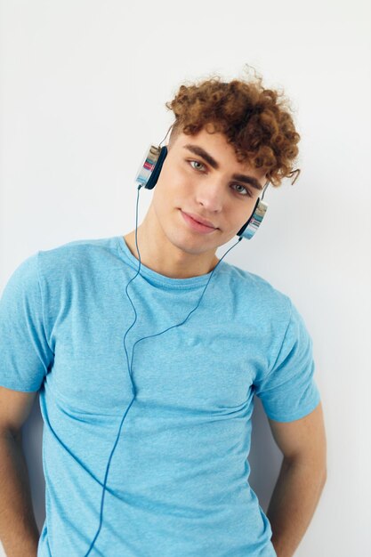 Chico guapo en camisetas azules auriculares moda fondo claro