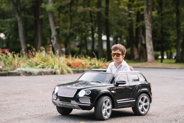 Chico guapo en un coche eléctrico negro en el parque