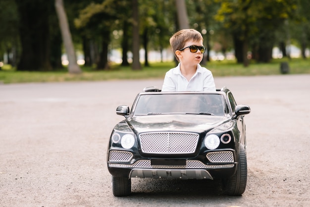 Chico guapo en un coche eléctrico negro en el parque