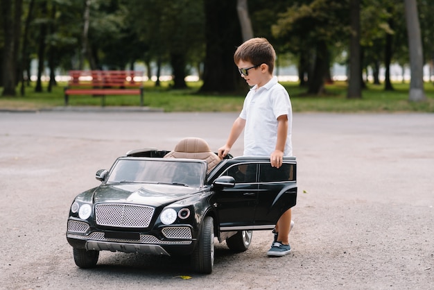 Chico guapo en un coche eléctrico negro en el parque