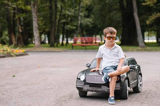 Foto chico guapo en un coche eléctrico negro en el parque