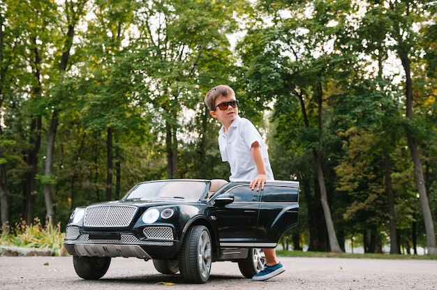 Chico guapo en un coche eléctrico negro en el parque