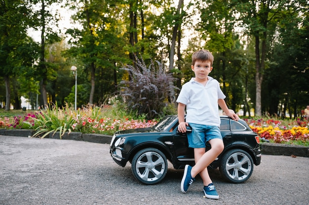 Chico guapo en un coche eléctrico negro en el parque