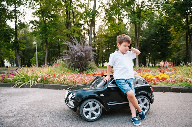 Chico guapo en un coche eléctrico negro en el parque