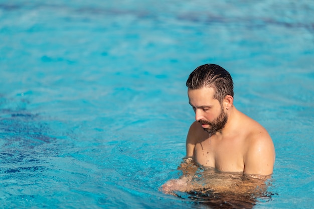 Chico guapo descansando en la piscina