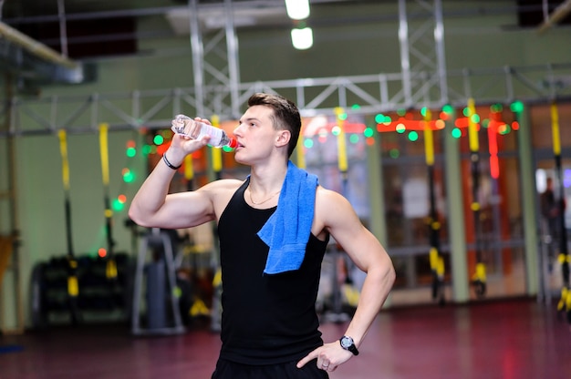 Chico guapo es beber agua en el gimnasio