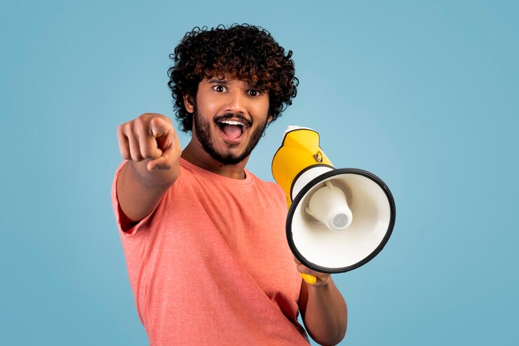 Foto chico guapo del este gritando a través del altavoz y gesticulando