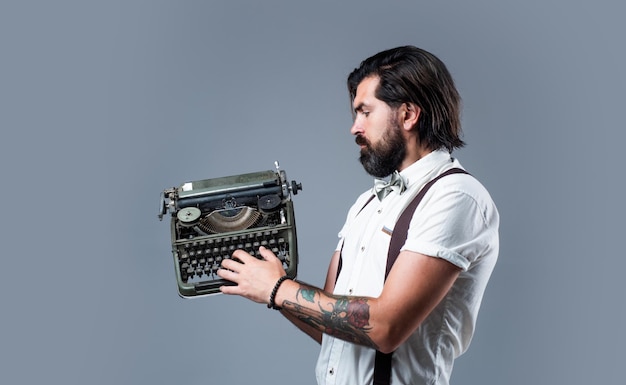 Chico guapo hipster con bigote y barba usa tecnología de máquina de escribir vintage