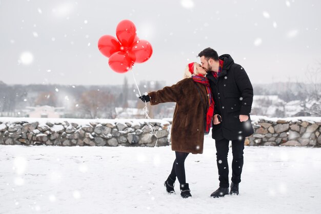 Chico guapo joven y chica con globos caminando en el día de san valentín