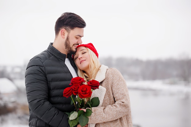 Chico guapo joven dando a una chica un ramo de rosas en el día de San Valentín