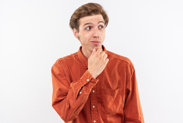 Chico guapo joven impresionado con camisa roja agarró la barbilla