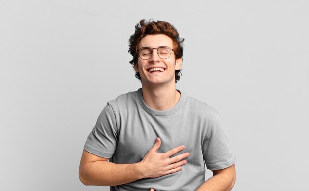 Chico guapo joven riendo a carcajadas de una broma hilarante, sintiéndose feliz y alegre, divirtiéndose