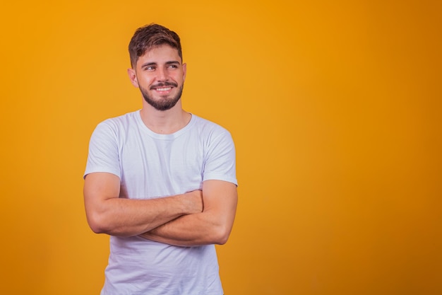 Chico guapo joven sonriendo mirando a la cámara con los brazos cruzados.