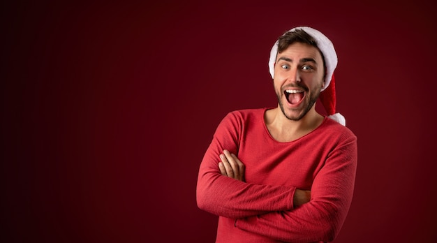 Chico guapo joven en suéter rojo y sombrero de Santa