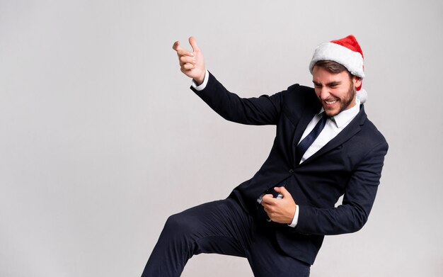 Chico guapo joven en traje de negocios y gorro de Papá Noel