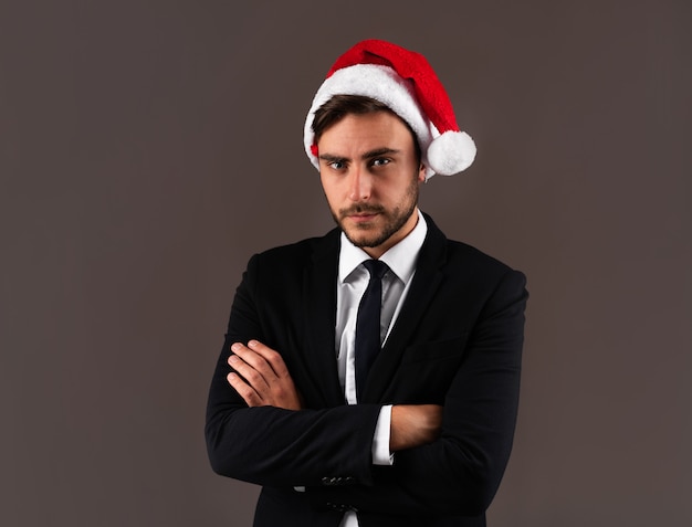 Chico guapo joven en traje de negocios y gorro de Papá Noel