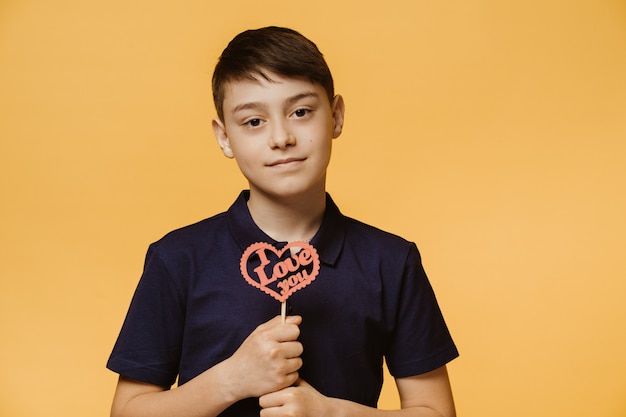 Chico guapo joven vestido con una camiseta azul oscuro, tiene corazón hecho a mano con la inscripción te amo. Feliz San Valentin . Las personas sinceras emociones.