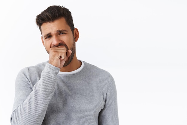 Chico guapo que se aburre hablando con un extraño sobre el personal al azar bostezando la boca abierta con el puño entrecerrando los ojos cansado de pie con aspecto de fatiga no le gustan los eventos aburridos fondo blanco