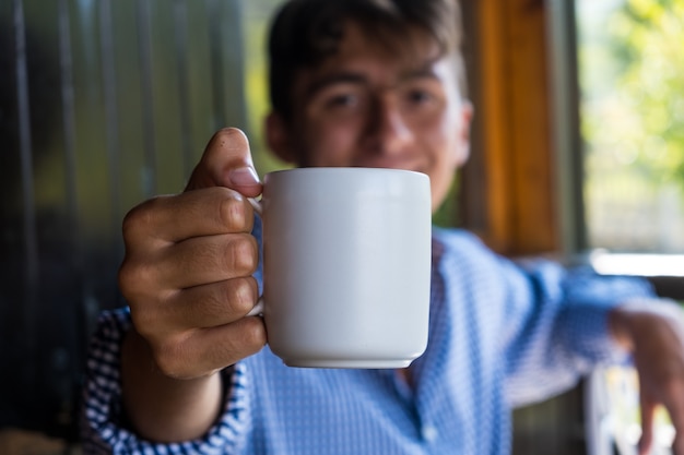 Chico guapo con taza de té blanco. Útil también como plantilla.