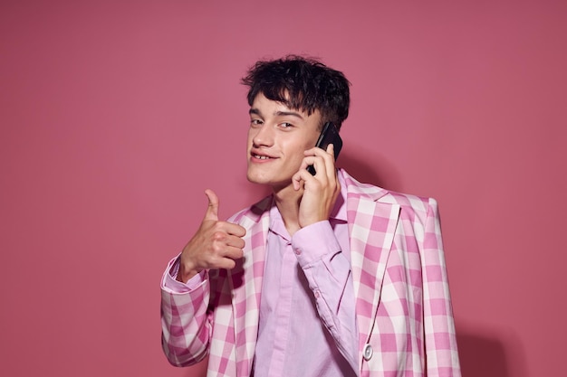 Chico guapo con un teléfono en la mano chaqueta rosa estudio de modelo de estilo elegante de moda