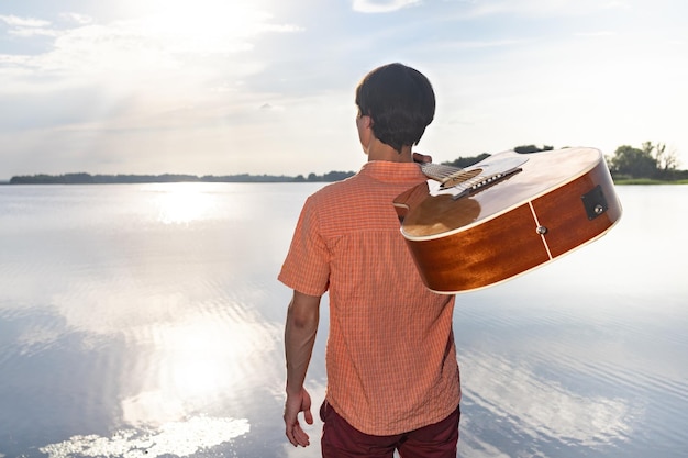 Chico con guitarra en la naturaleza