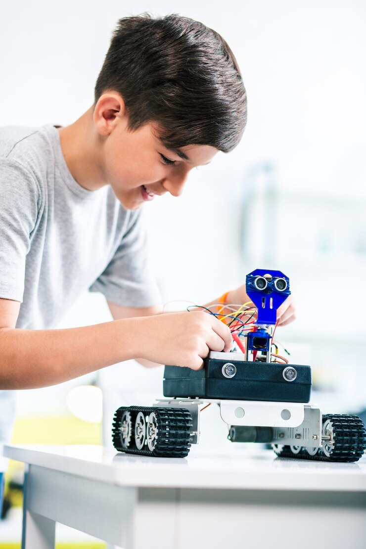 Foto chico inteligente agradable que construye un robot mientras se prepara para el concurso de ingeniería en casa