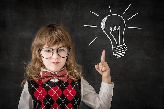 Chico inteligente en clase. Niño feliz contra la pizarra. Concepto de educación