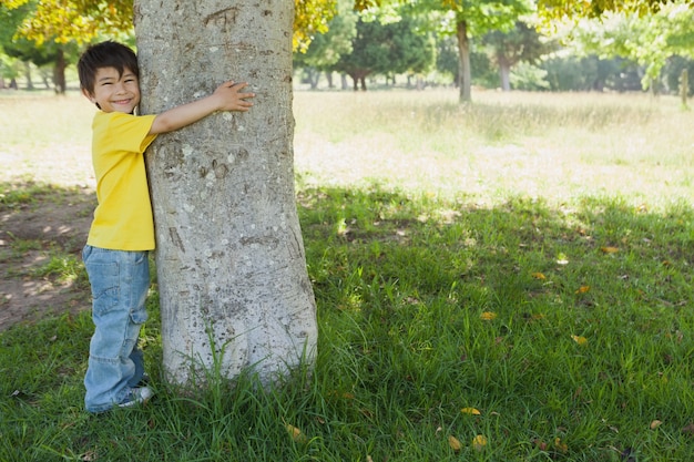 Chico joven abrazando un árbol en el parque