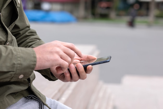 Un chico joven en la calle se sienta en el teléfono.