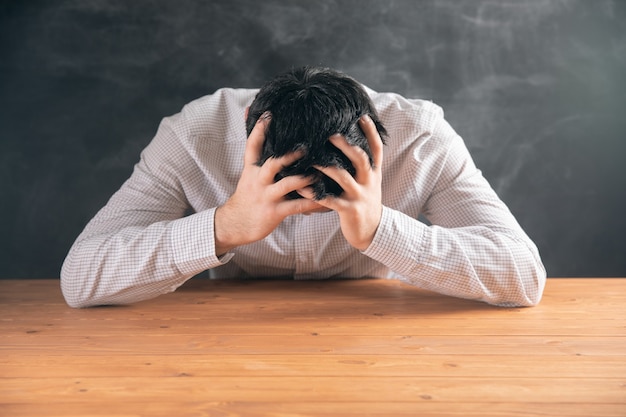 Chico joven cansado con la cabeza entre las manos.