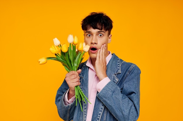 Chico joven en chaqueta de mezclilla con un ramo de flores posando romance