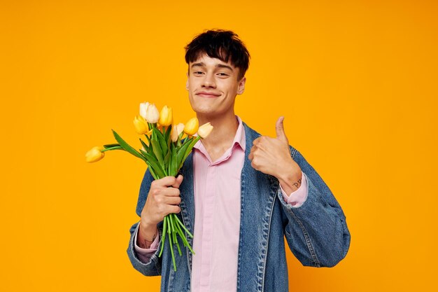 Chico joven en chaqueta de mezclilla con un ramo de flores posando romance