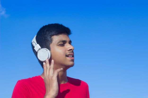 Chico joven chico guapo adolescente escuchando música con auriculares en emociones de estado de ánimo relajado