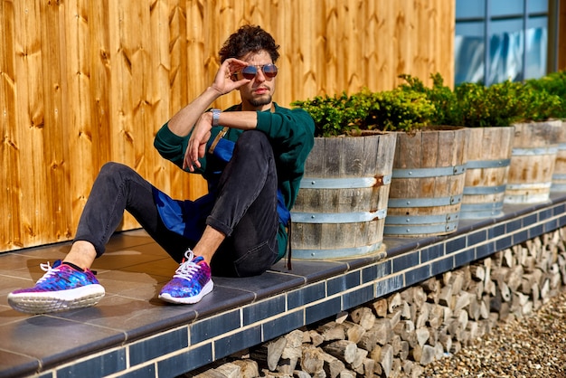Chico joven con un delantal se sienta en la terraza de una casa de madera.