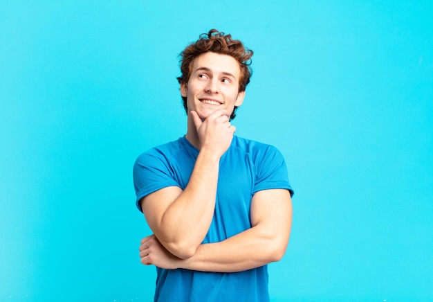 Chico joven deporte sonriendo felizmente y soñando despierto o dudando, mirando hacia el lado