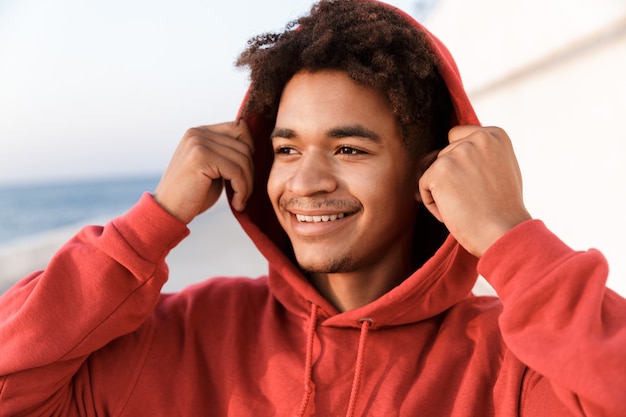 Chico joven deportes al aire libre en la playa mirando a un lado