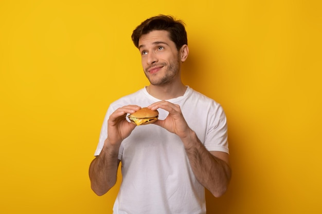 Chico joven divertido con hamburguesa en el estudio