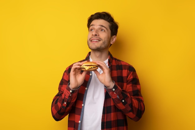 Chico joven divertido con hamburguesa en el estudio