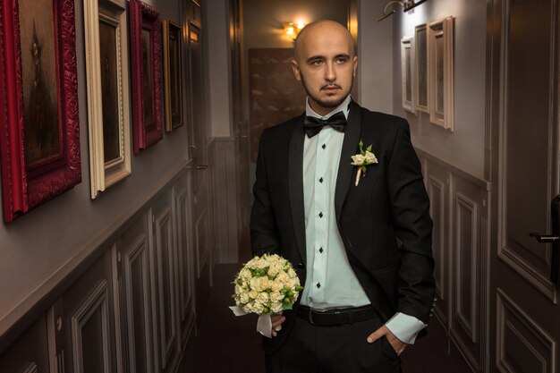 Chico joven elegante con un traje con un ramo de rosas