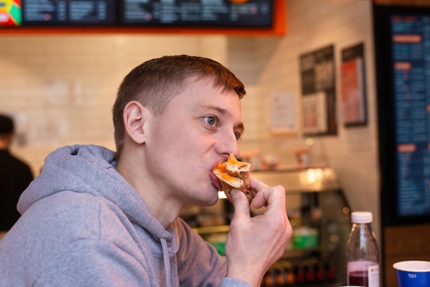 Un chico joven está comiendo pizza en un restaurante de comida rápida.